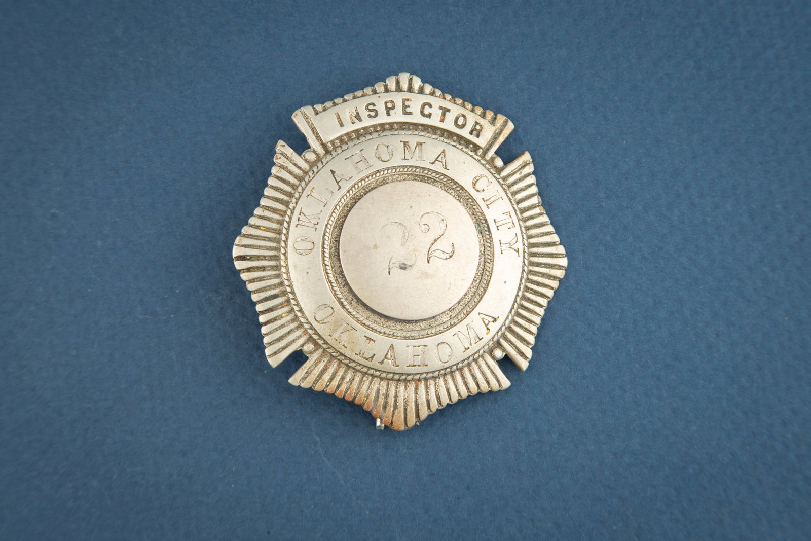 Beautiful old Sunburst shaped Badge marked “ INSPECTOR/ OKLAHOMA CITY /OKLAHOMA?? with “22: Beautiful old Sunburst shaped Badge marked “ INSPECTOR/ OKLAHOMA CITY /OKLAHOMA” with “22” in center. Has lots of patina, back has spring pin with broken off catch, and measures 2 3/8&