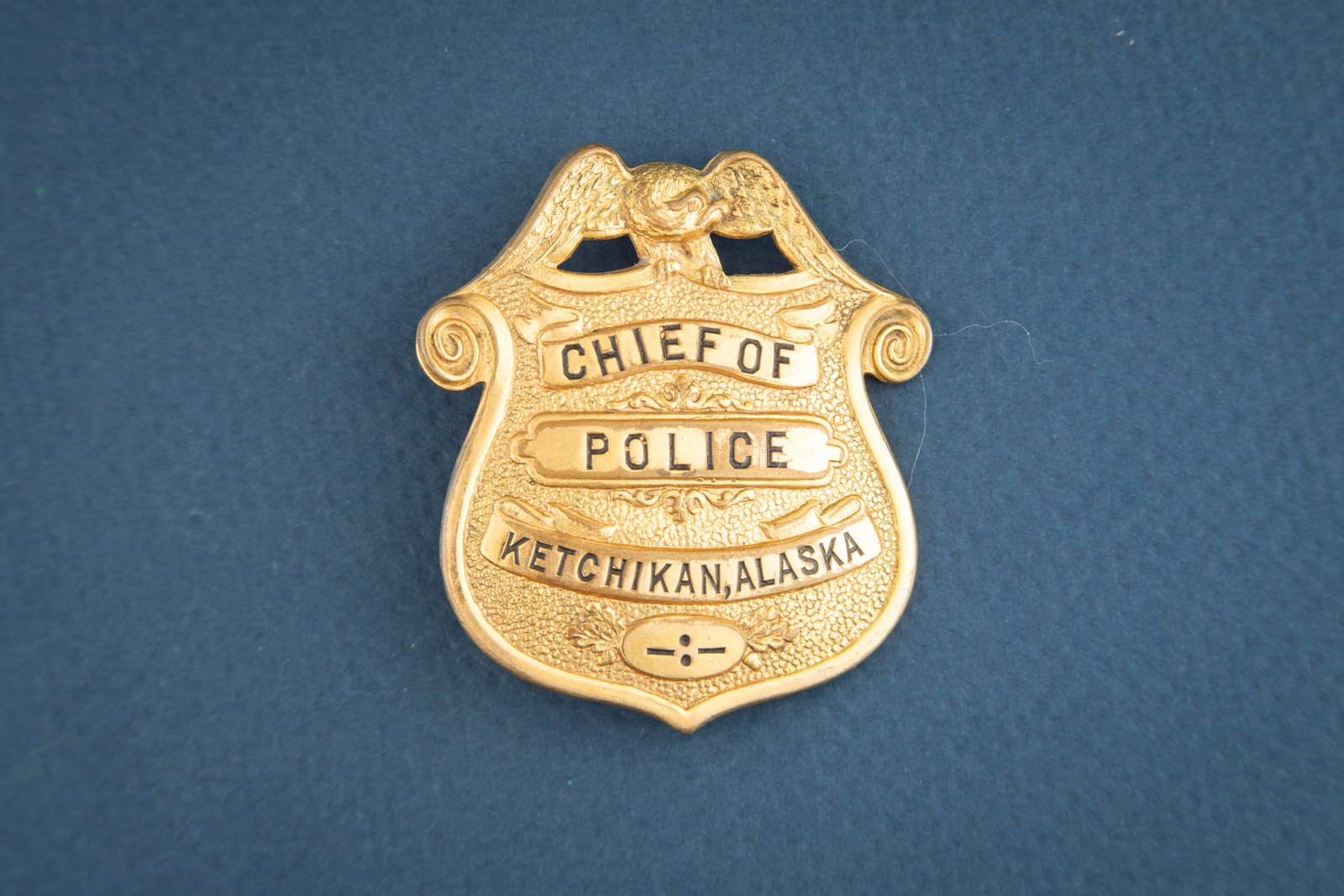 Vintage gold tone Shield Badge with Eagle Crest marked “CHIEF OF/POLICE/KETCHIKAN, ALASKA??,: Vintage gold tone Shield Badge with Eagle Crest marked “CHIEF OF/POLICE/KETCHIKAN, ALASKA”, nice old badge has great pin with tongue catch, measures 2 1/8” T x 1 7/8” W. Hallmarked