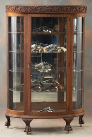 Antique triple curved glass, oak China Cabinet with highly carved bulk head and four claw feet,