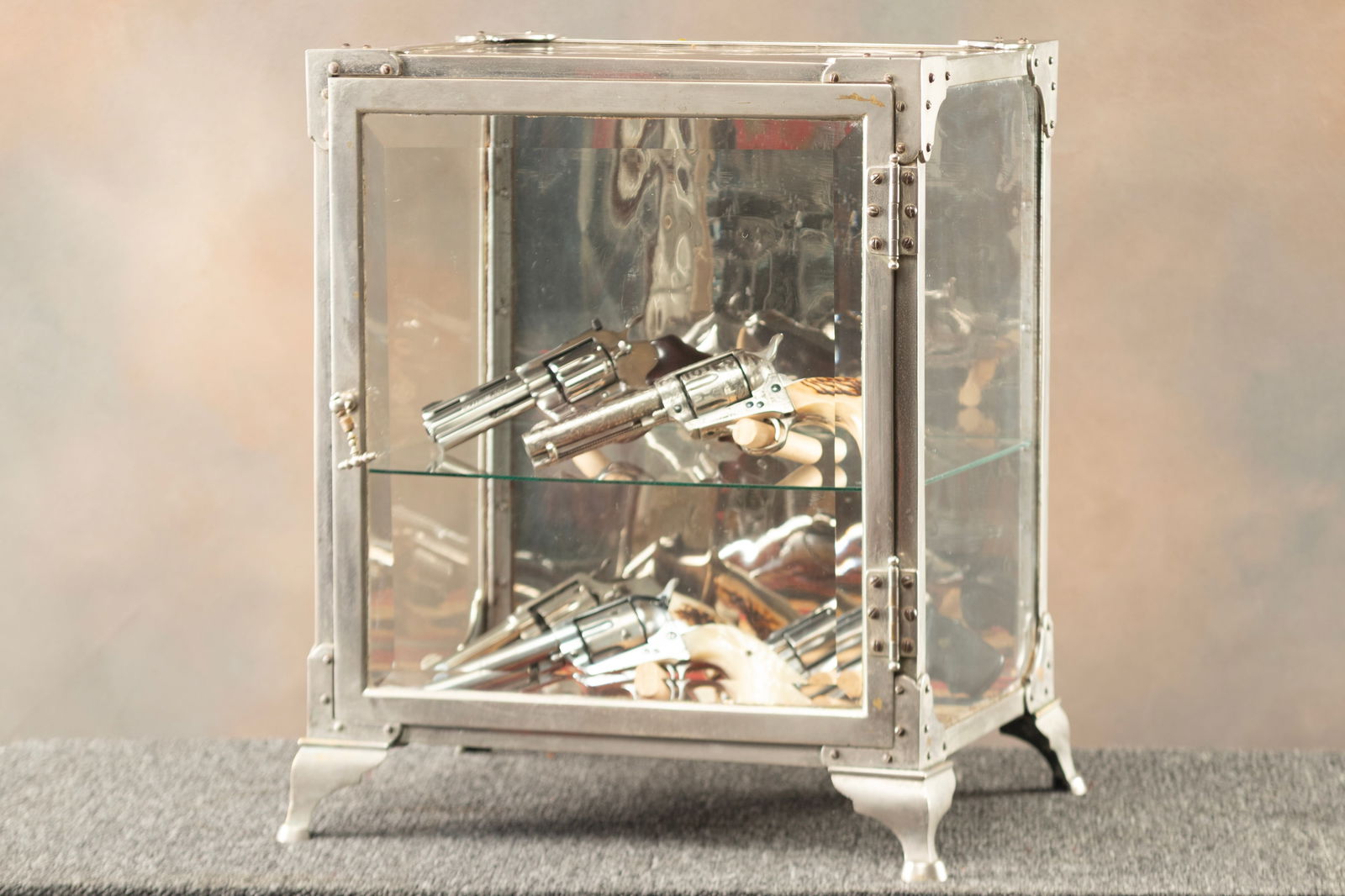 Unique vintage nickel and glass, single door, counter top Showcase with wide beveled glass front: Unique vintage nickel and glass, single door, counter top Showcase with wide beveled glass front door and footed base, measures 22 1/2" T x 18" W x 14" D. Extremely well made high quality case. Revolv