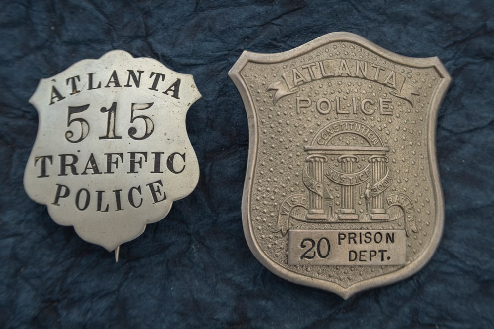 This lot consists of two Badges to include: (1) Large vintage Shield Cap Badge marked “ATLANTA/ (1 of 2)