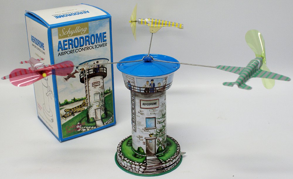 Tin Windup SCHYLLING 'AERODROME' Airport Control Tower: Vintage Tin Lithographed Wind-up SCHYLLING 'AERODROME' Airport Control Tower in the Original Box. Has 3 planes that spin around the tower when wound. Stands 6-1/2" tall. Old store stock. (Packaging ha