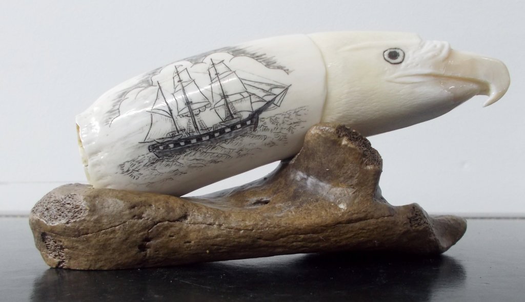 Scrimshaw Whale Tooth w/ Base: Genuine Scrimshaw Whale Tooth on a Petrified Wood Mount. This whale tooth was carved in the shape of a bird head. This piece also features intricately carved nautical and whaling themed artworks done 