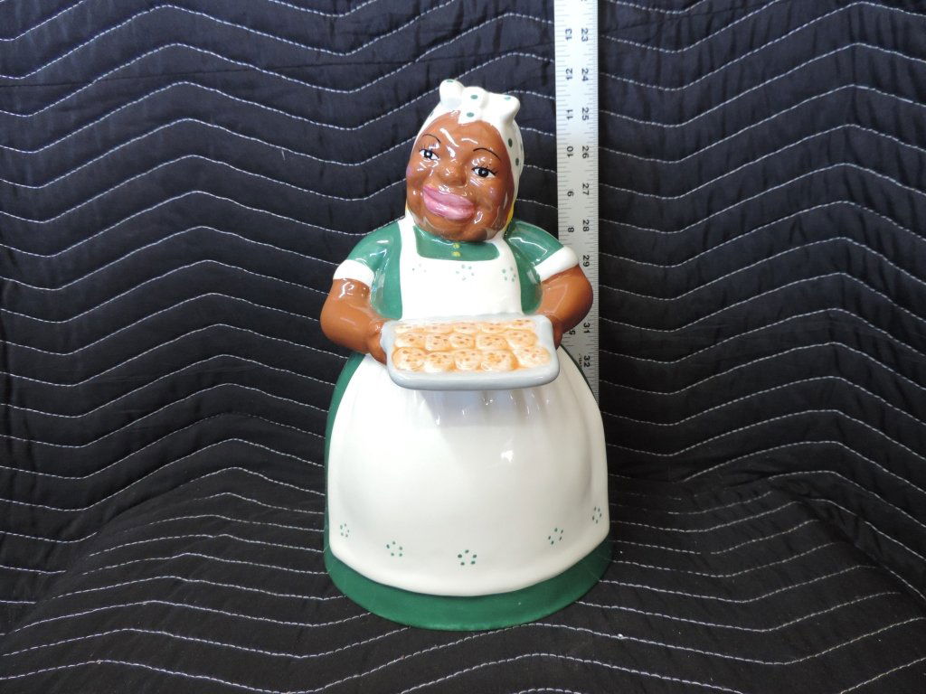 Cookie Jars: Great Black Americana cookie jar. This lady is wearing a green dress with a white apron and white bonnet that allows the yellow earrings to pop through. She is holding a tray of cookies and is in mint