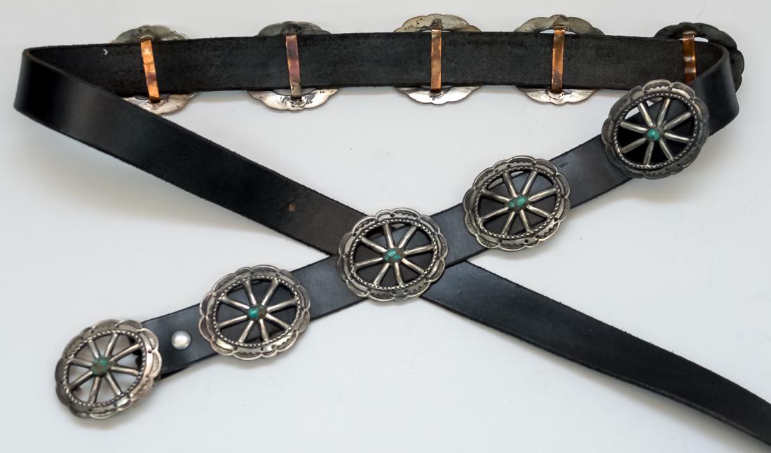 Silver & Turquoise Concho Belt by Nellie Tso: Fine engraved and hand tooled belt with ten silver conchos, oval eight spoked wheel with turquoise in center of each. Signed on reverse of buckle, "N. Tso," total length 64." All on black leather. Nel
