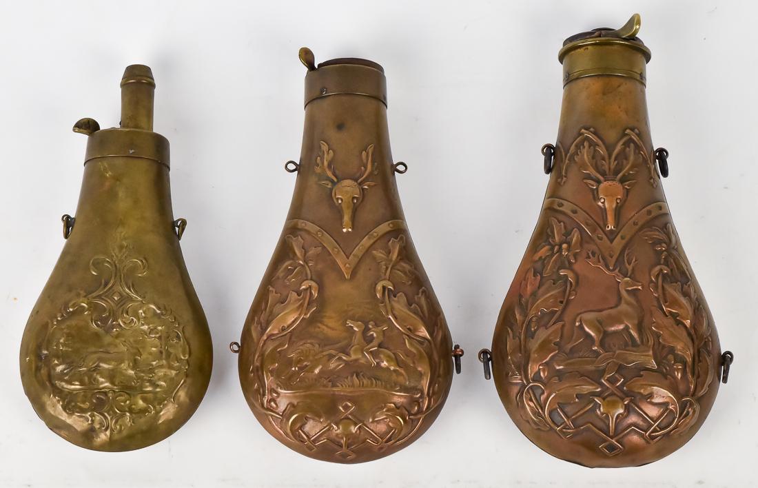Three Game Shot Flasks: All brass including one with buffalo hunt with Indian on horseback with stag head above, and fox head below, with oak leaf surround, double sided, 6 3/4" long; plus standing stag with oak leaf surroun