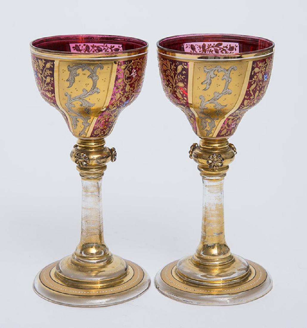 Pair Moser Decorated Rhine Wine Glasses: With ruby glass bowls and clear stems, blow glass with polychrome enameled floral decoration on bowls, applied flowers on stems with gilt highlights, 3" diameter x 6 3/4" high.