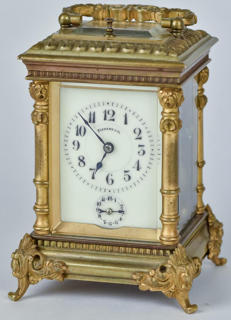Tiffany & Co Carriage Repeater Clock: Enameled dial with Arabic numerals marked Tiffany & Co. with alarm set dial below, in ornate rococo style brass case with beveled glass front, rear door, sides and top with folding handle and cabriole