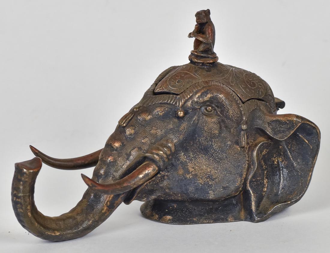 Bronzed Figural Elephant Inkwell: In the form of a bust of an Indian elephant with monkey playing a flute on top of head, monkey acts as handle to lift hinged lid to expose interior glass lined well, marked on base Rogers Smith & Co. 