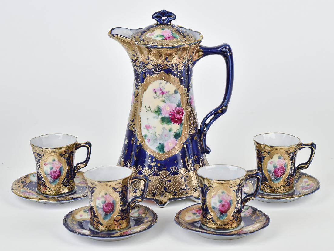 Nippon Cobalt Blue Chocolate Set: Footed chocolate pot with heavy gold and four floral panels, Four cups and saucers with matching decoration. Maple leaf backstamp. 10 1/2" high. Good condition.