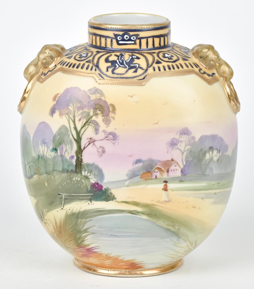 Nippon Scenic Vase: Hand painted, home scene with lake and lady walking below. Unusual phoenix bird and horse ride decoration at top, surrounded by gold decoration, with rams head handles. M within wreath backstamp. 8" H