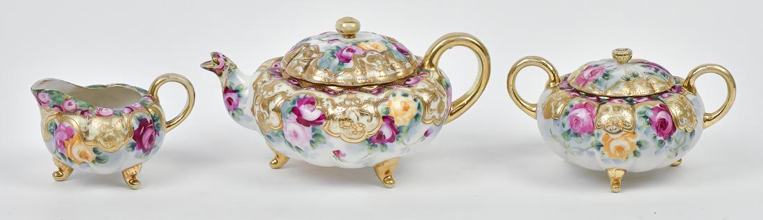 Nippon 3 Piece Tea Set: With rose and gold decoration. All three pieces are footed. Maple leaf backstamp. Teapot has small chip inside rim, otherwise good. 5 1/2" high x 8" wide.