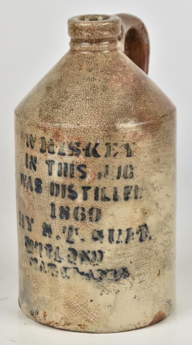1860 Maryland Stoneware Whiskey Jug: White glazed stoneware with stenciled blue inscription reading Whiskey In This Jug Was Distilled 1860 T.S. Guit Maryland, with C scroll handle, 4 /4" diameter x 8" high. Condition spider line Crazing,
