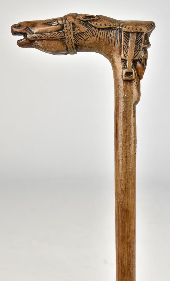 Carved Horse Cane: 19th century maple with crook handle carved in the form of a horses head and neck with English type saddle on neck, single piece with 1" brass ferrule, total length 34". Condition minor shrinkage line