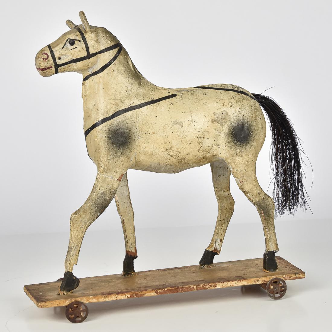 Early German Horse Pull Toy: Mid to late 19th century, wood with composition in original black, white and red painted finish with horse hair tail, mounted on original wood base with four tin wheels, 11 x 3 1/4 x 12 1/4" high. Con