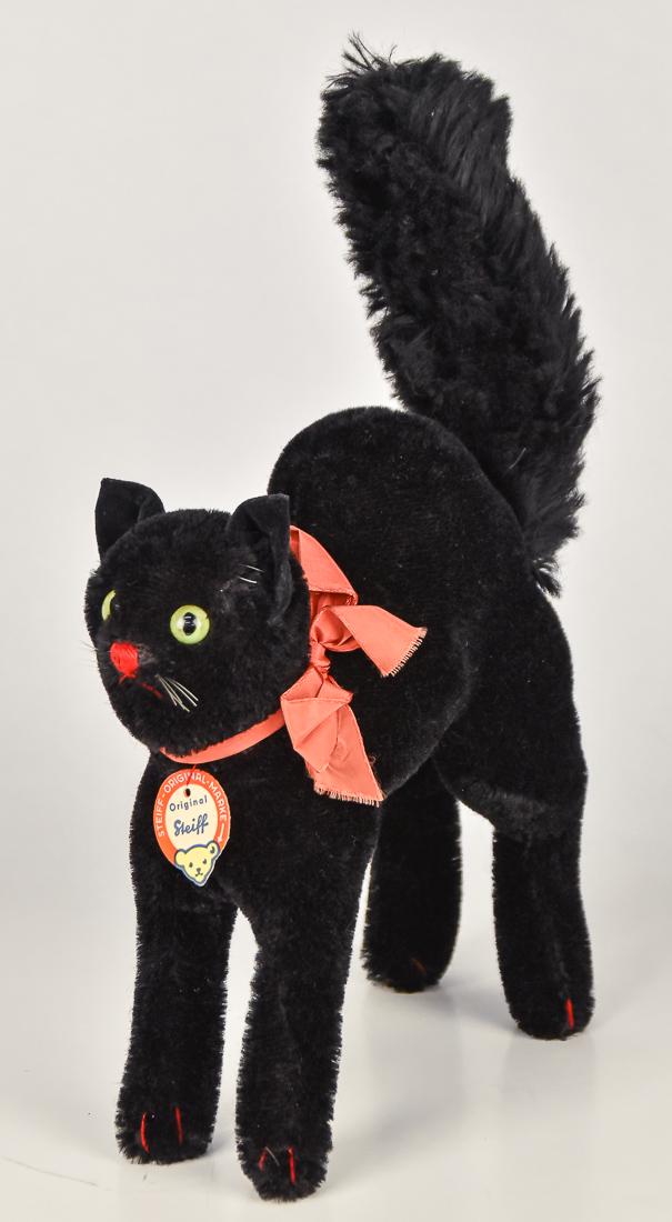 Steiff Halloween Black Cat: Black mohair with excelsior stuffing, standing with arched back and bristled tail, red ribbon at neck with original printed Steiff tag, green glass eyes, whiskers and red thread sewn nose & mouth, 8 x