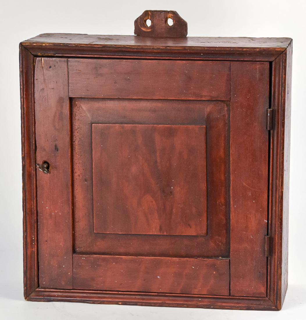 Shaker Attribution Red Washed Early Hanging Cupboard: Pine circa 1850 with cove molded edges and paneled door with lock and key, tab extending from back for hanging, stamped C.L. Clark on top, interior with one shelf, 16 1/2 x 8 1/2 x 18" high. Condition
