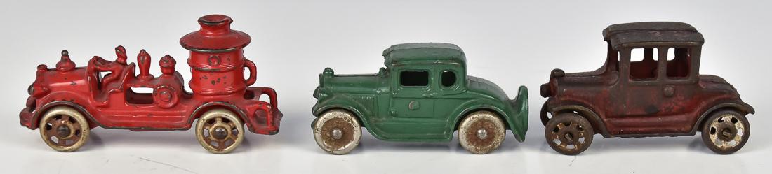 Three Cast Iron Toys: Including fire engine in original red paint with stamped steel tires, 5 x 1 3/4 x 2 1/2" high; plus 2 door sedan with pressed steel tires in original green paint, 4 1/4 x 1 3/4 x 2" high; and 2 door F