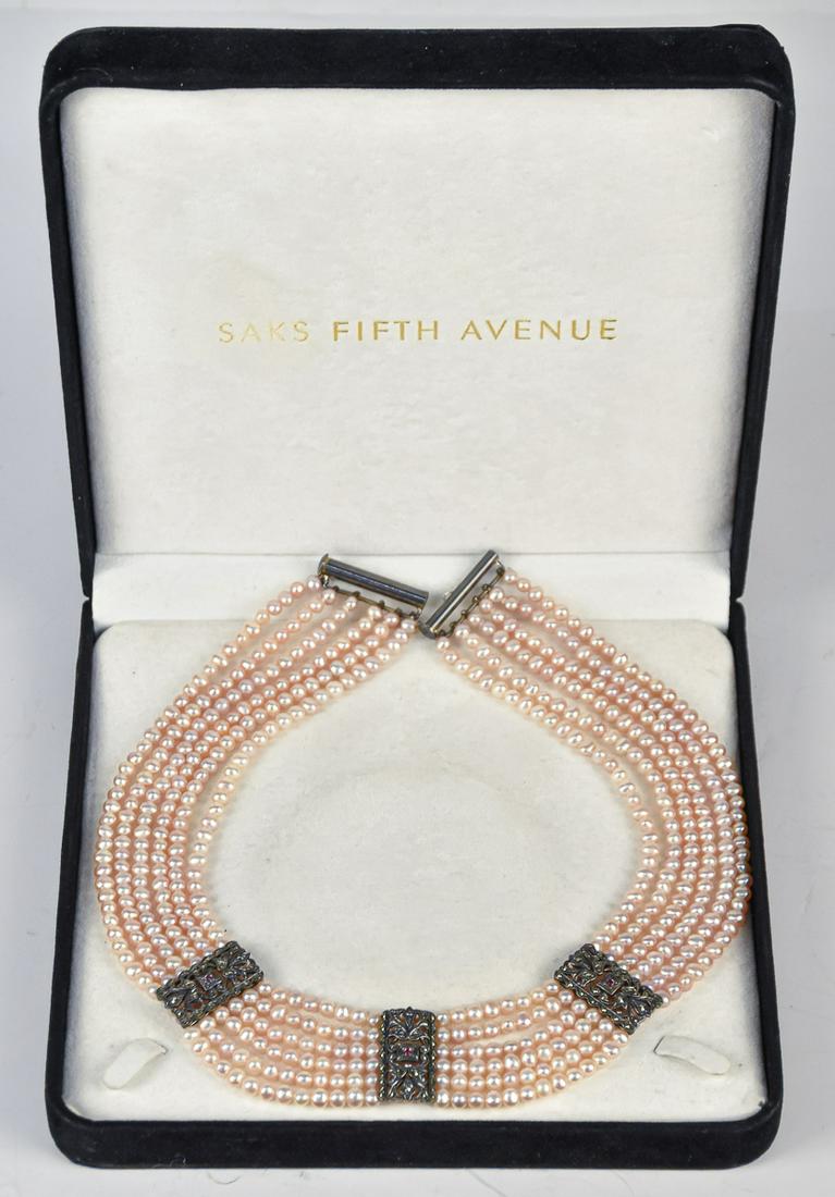 Pearl & Diamond Necklace form Saks: In original black velvet covered box. This lovely necklace has sterling clasps with six stands of natural pink pearls with 228 total pearls and three sterling open-work mounts between pearls set with 
