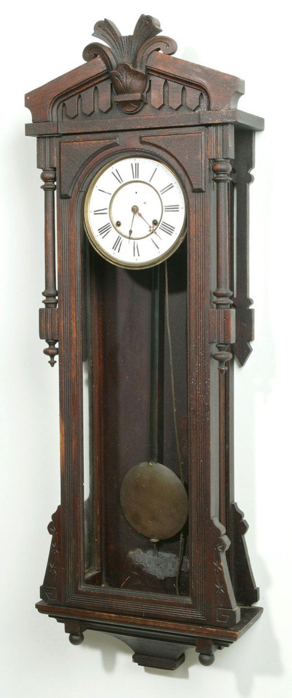 ANSONIA WALL CLOCK, BAGDAD MODEL: Oak case, glass sides, weight model with weights missing. An original old finish as found clock. Center top carving, bottom finial and second hand missing. Chip to 8" porcelain dial. 48" h x 16" w x 6