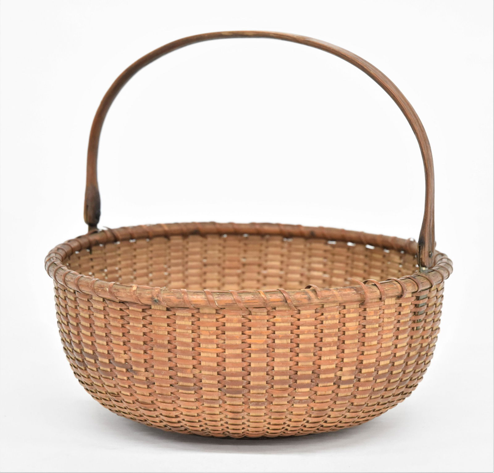 Nantucket Lightship Basket: 19th century with turned wood base, bent hickory swing handle, split cane, 10" diameter x 4" high less handle, 9" high with handle, nice old patina, Condition coil breaks at lip, still Very Good.