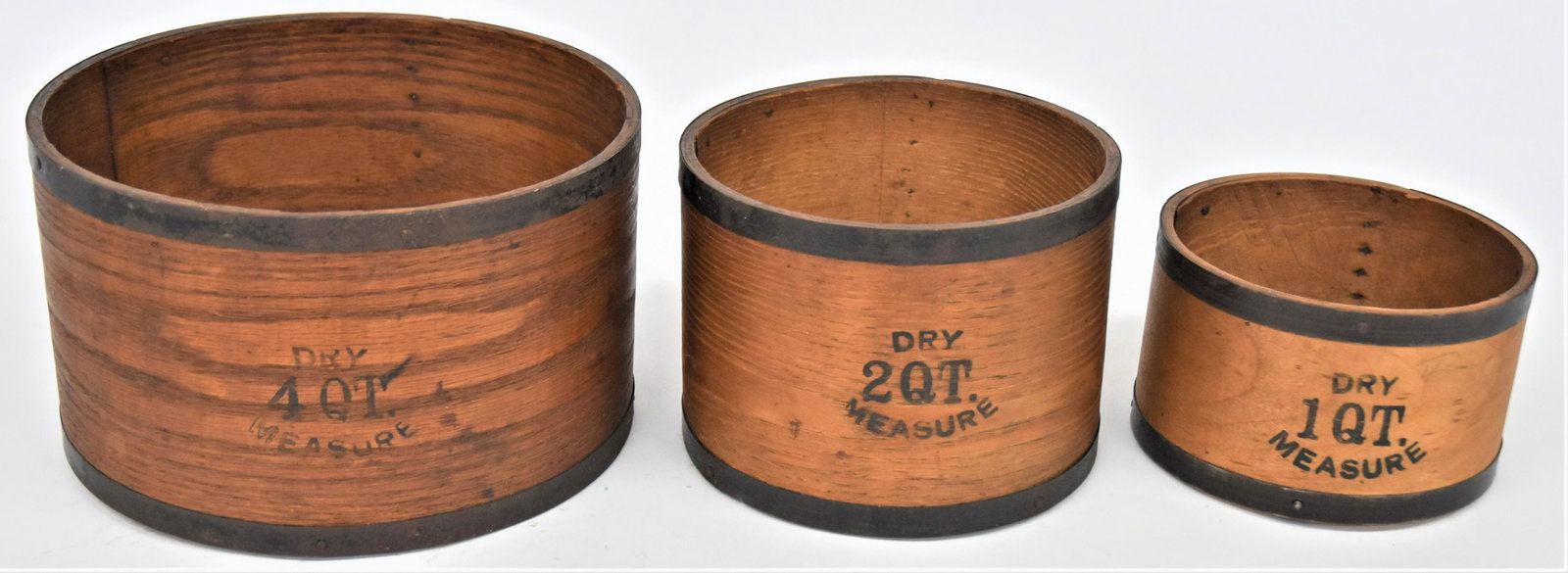 Signed N.H. Bentwood Measures: Graduated set of three with tin bands at top and base, each branded on interior base Made/By/EB Frye & Son/Milton/NH; largest is 9" diameter x 5 1/2" high and marked on side Dry/4 QT./Measure; middle 