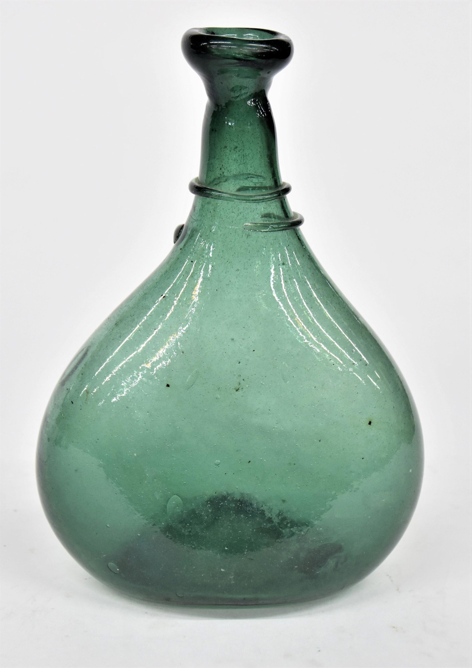 Blown Glass Bottle: Deep emerald green hand blown with tooled flared lip and applied ribbon coil around neck, pushed up base with snap pontil, 6 1/2 x 3 1/2 x 10" high. Condition Fine.