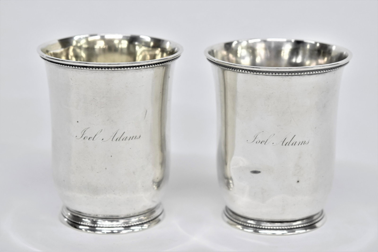 Pair Of Coin Silver South Carolina Julep Cups: Circa 1840's barrel form with beaded foot and rim, marked with rectangular touch mark with W. Glaze and 2nd vertical oval touch with W&H, engraved on front of each Joel Adams, 3 1/8 x 3 3/4" high, tot