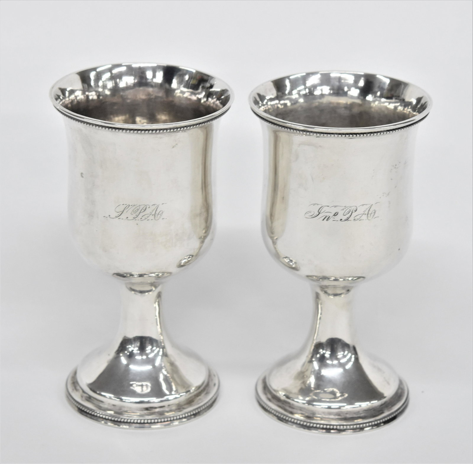 Pair Southern Coin Silver Chalices: Circa 1840's with beading at lip and foot (see lots 96-98) engraved on fronts S.P.A. & Jno. A., each with matching but unclear touch mark on underside of bowl, 3 1/2" diameter x 6 1/2" high. These are