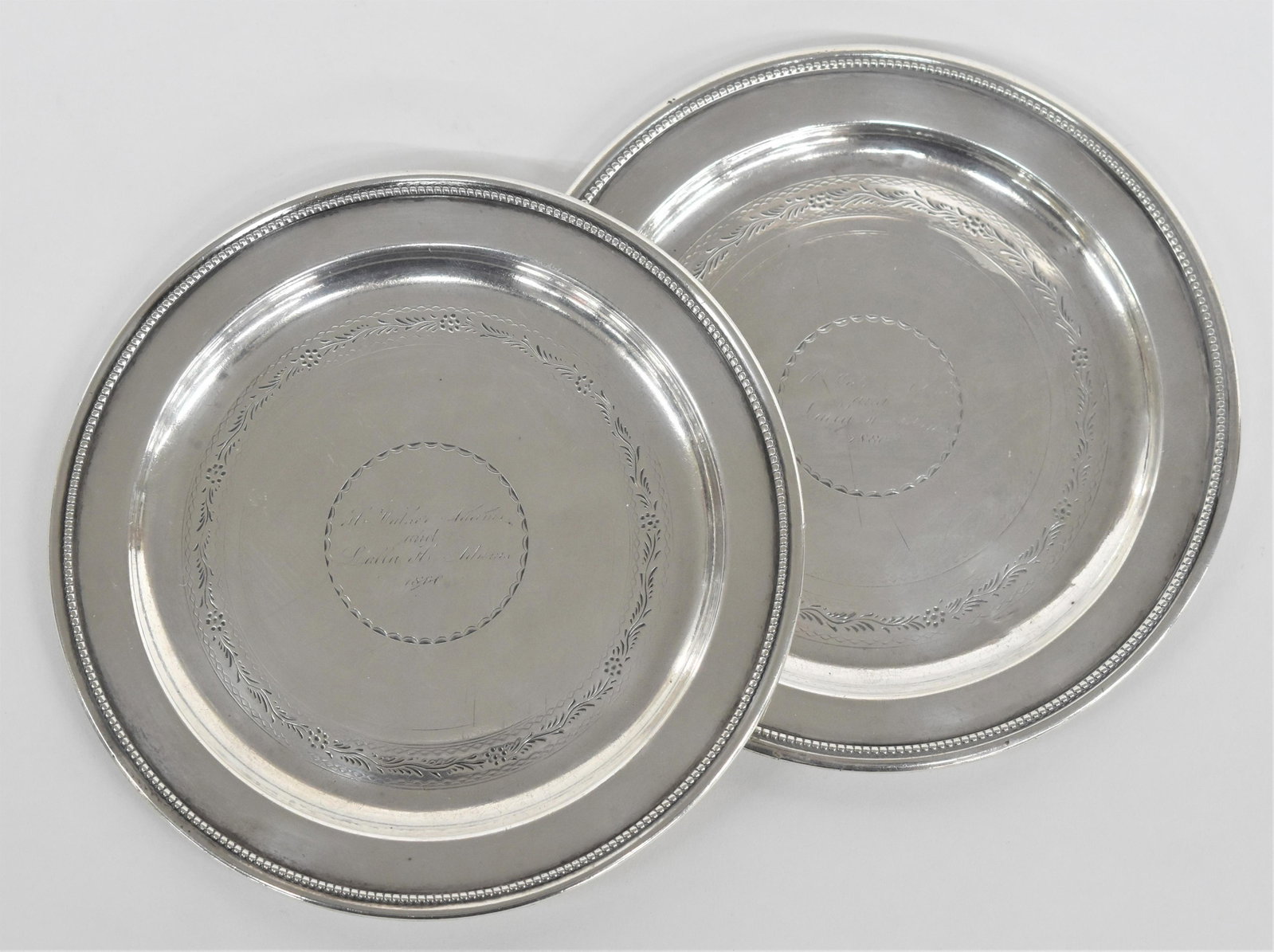 Pair Coin Silver Salvers: Unmarked with beaded edge and floral engraved band in bottom with central inscription in each reading H ---- Adams/and/Lulla H. Adams/1880, 5 1/2" diameter, total weight 6.55 ozt. Condition Fine.