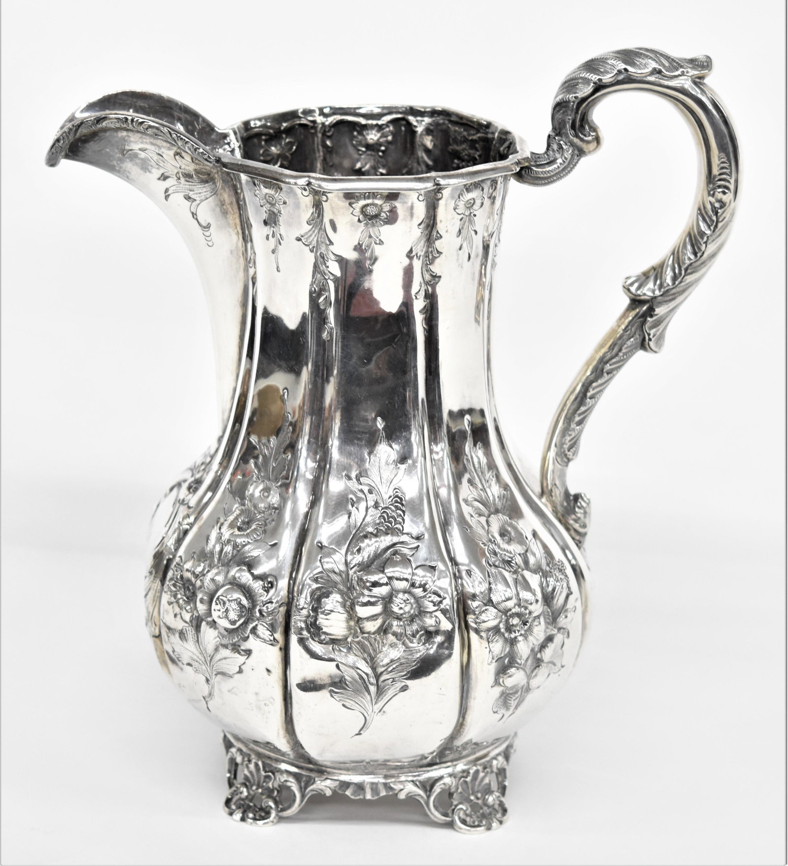 American South Carolina Coin Silver Water Pitcher: Circa 1840-50's with paneled bulbous form with heavy floral chasing, acanthus leaf C scrolled handle, and pierced shell and floral scrolled feet, escutcheon on front with AGA (Adams family, see above 