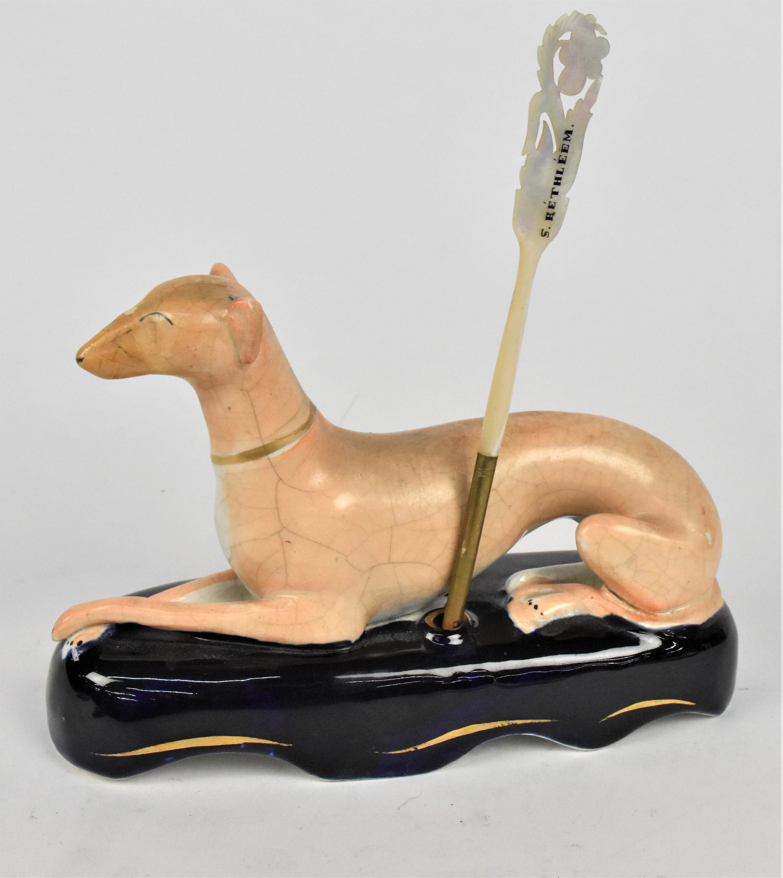 Early Staffordshire Figural Pen Holder: Greyhound in polychrome paint on cobalt base7 1/2 x 3 x 5" high, with dip pen in carved MOP and gilt brass, 7" long. Condition repair to snout, else Fine.