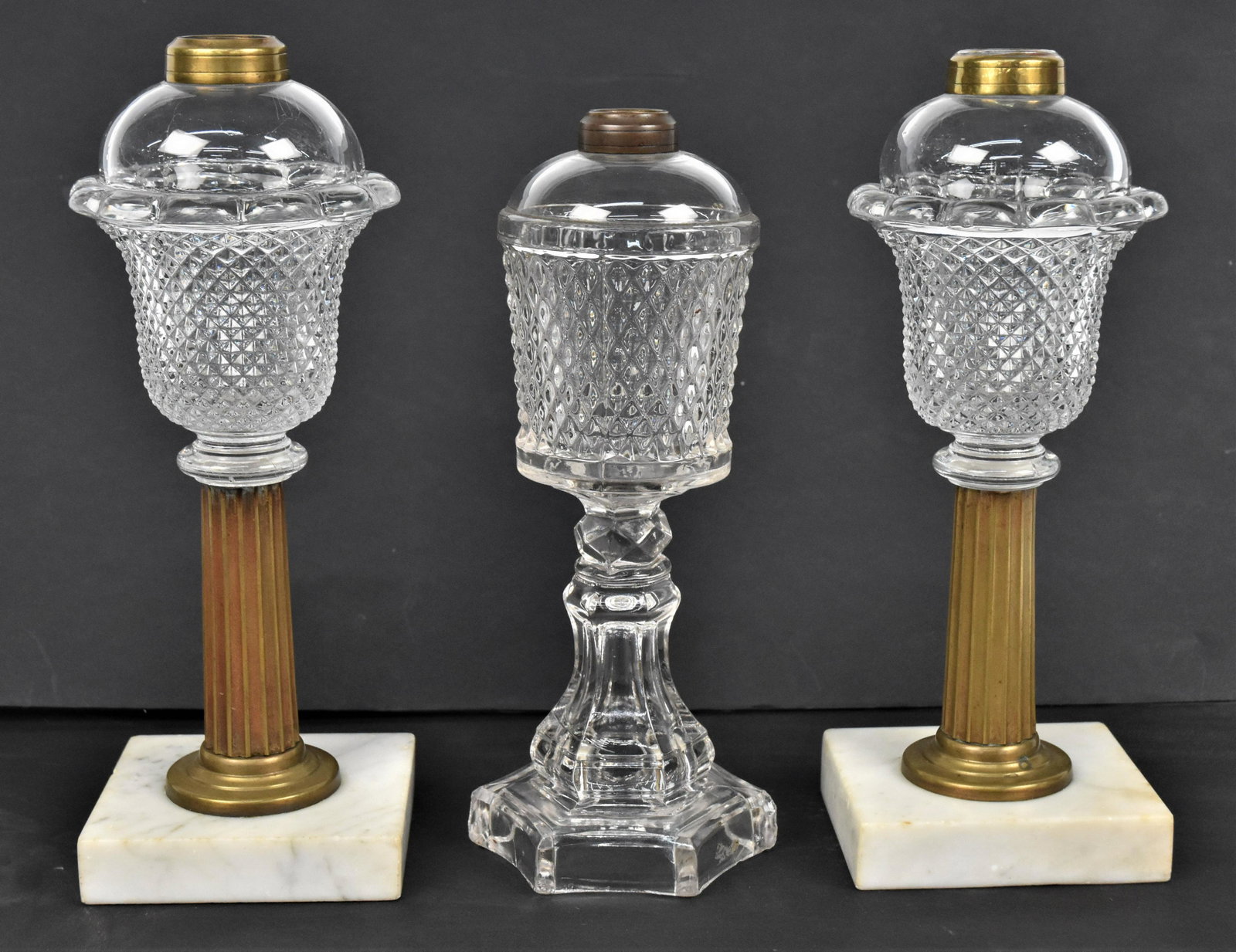 Diamond Point Whale Oil Lamps: Lot of three, including a pair of Flint glass with brass fluted columns and square white marble bases, 4" square x 10 1/2" high; and one with hexagonal base, 4" diameter x 10" high. Condition all lack