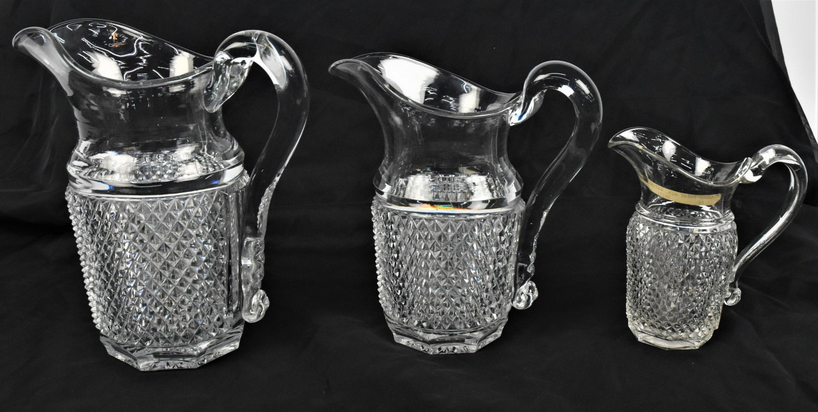Flint Diamond Point Pitchers: Graduated set of three, all clear flint with applied C scroll handles with tooled notching on lower terminals, circa 1830-40, largest is 8 x 5 x 9 1/4" high; smallest, which is quite rare size is 5 1/