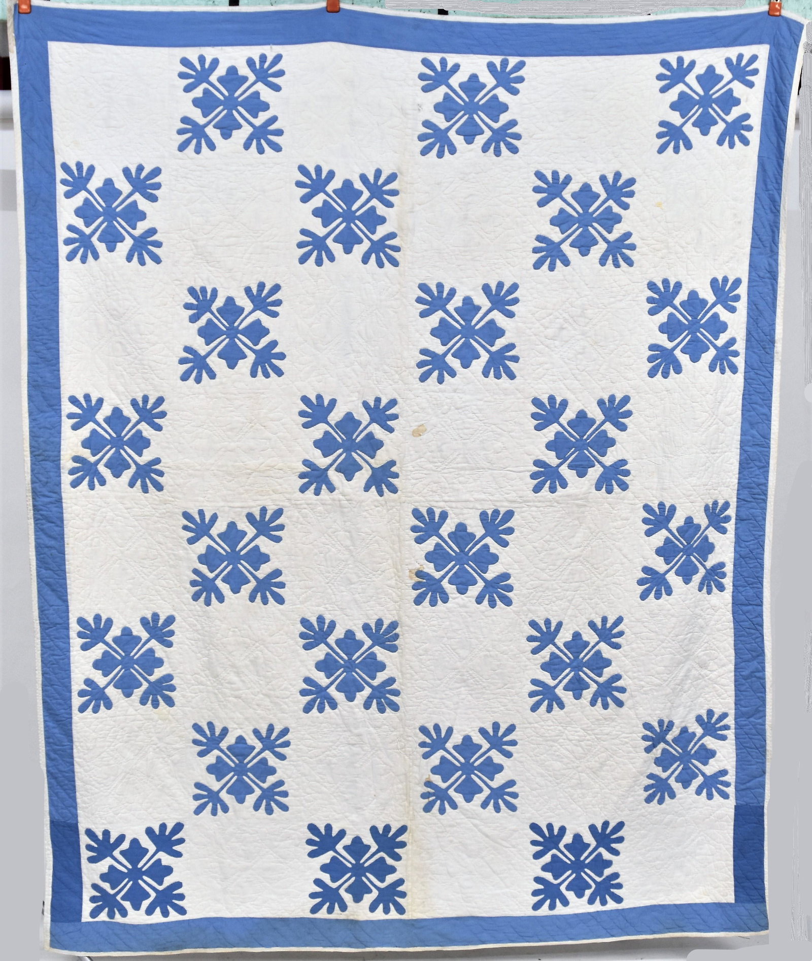 Early Appliqued Quilt: Circa 1870-90 in blue on white stylized floral pattern with wide blue border, all hand quilted, 72 x 88". Condition some minor stains, still Very Good.