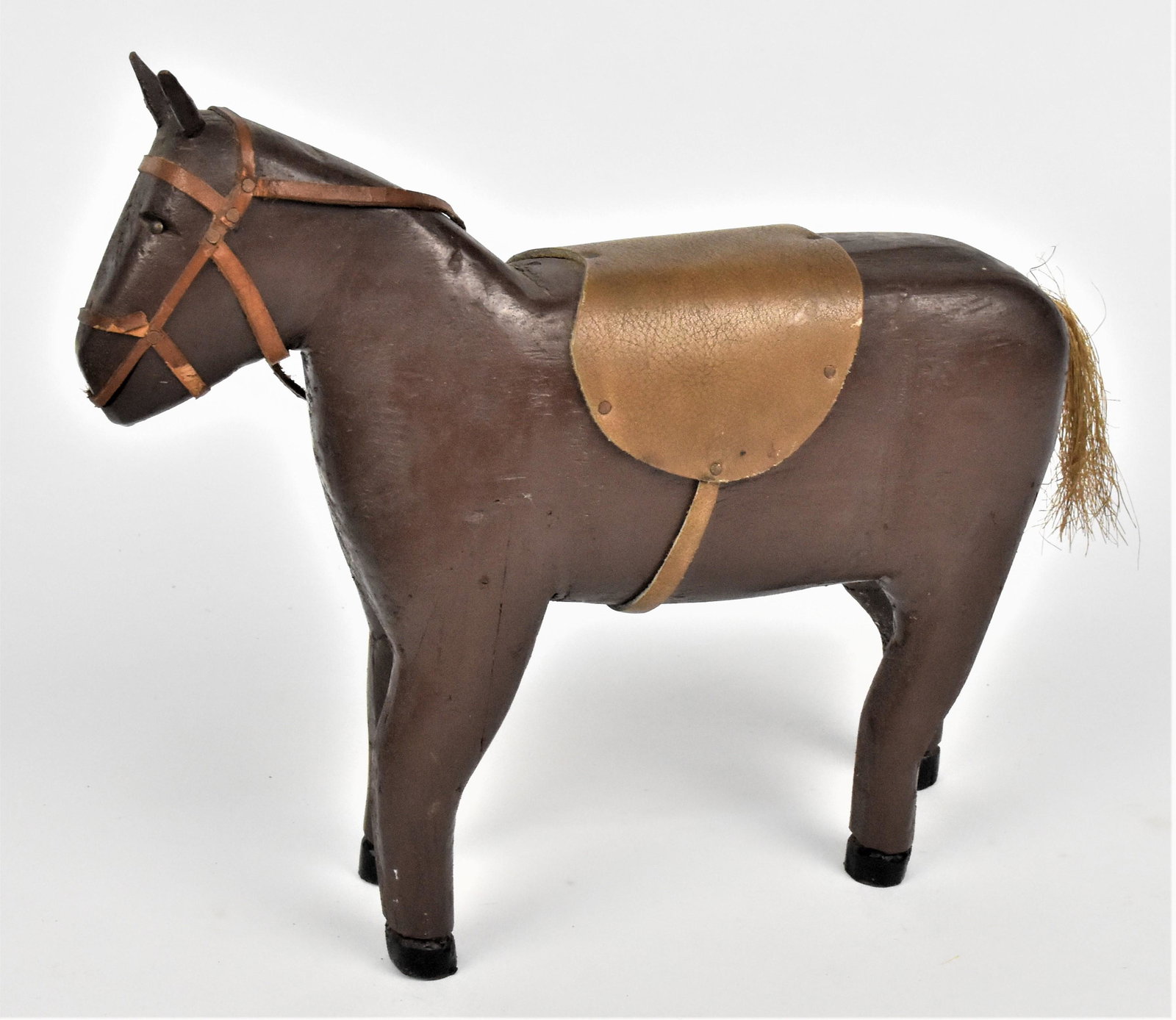 Folk Art Toy Wood Horse: Hand carved early 20th century in original brown & black painted finish with brass tack eyes, leather saddle and bridle, hemp tail, 12 x 3 x 9 3/4" high. Condition Fine.