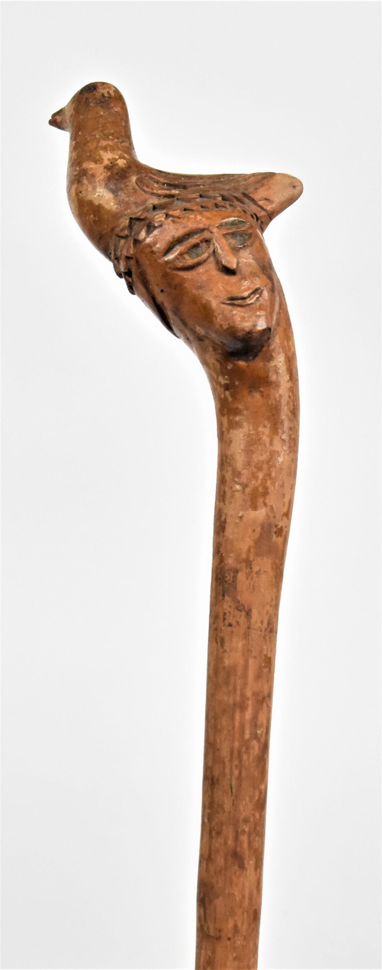 Folk Art Carved Walking Stick: Circa 1880 in single piece maple, with knob carved in the form of a mans head with a nesting bird on top, tapered shaft and never had a ferrol, nice old polished patina, total length 36 1/2". Conditio