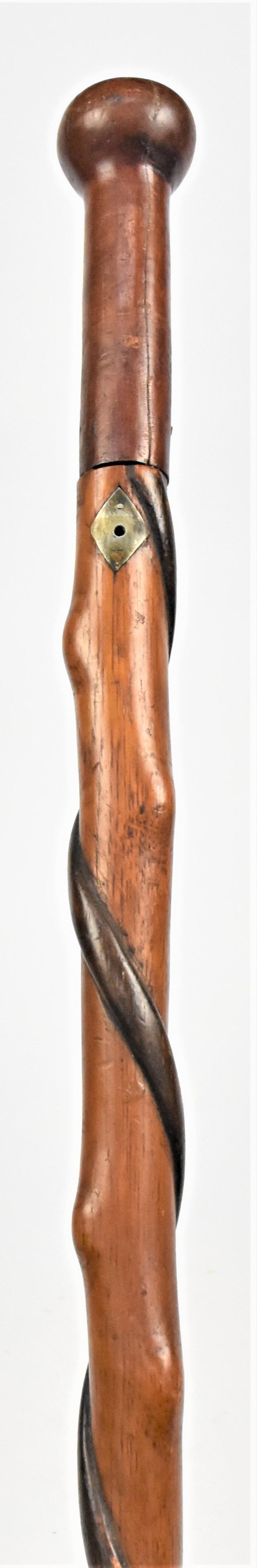 Folk Art Carved Walking Stick: Circa 1870's two piece with 5" knob in cherry, mounted on spiral carved tapered chestnut, with relief spiral band stained a dark walnut color, diamond form escutcheons just below knob in coin silver w