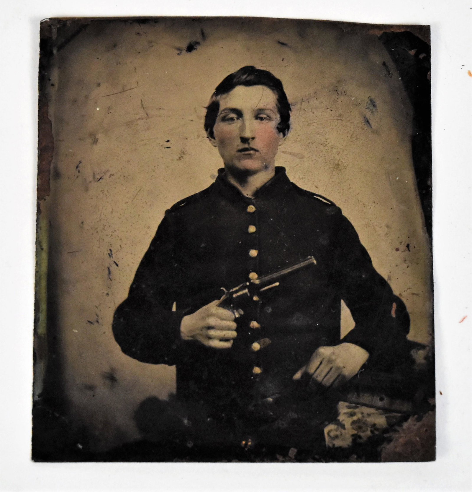 Tintype of Armed Union Soldier: Sixth plate tintype half length portrait of a young looking Union soldier with a Smith & Wesson revolver, wearing a nine button shell jacket with shoulder bars, likely a young officer. Condition minor