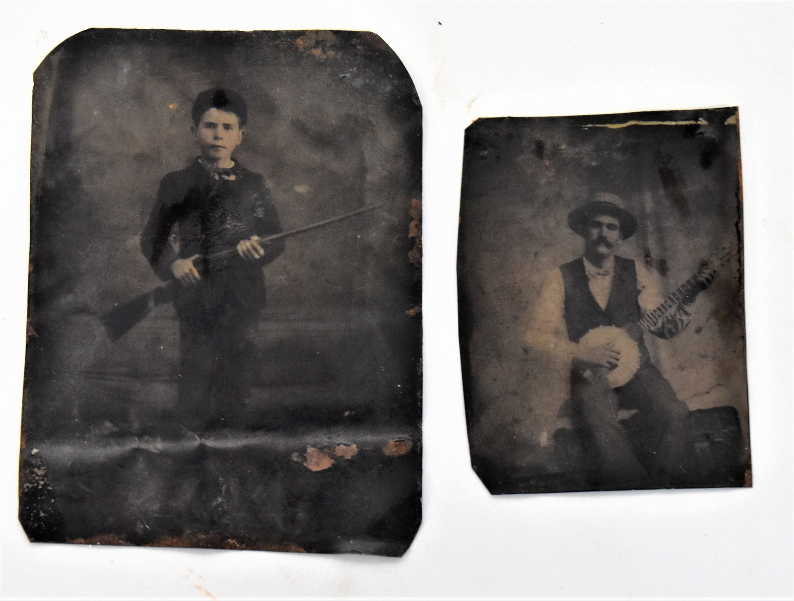 Two Interesting Tintype Photos: Including 3 ½ x 4 ½” photo of young boy holding a rifle; and cdv sized tintype ofman in straw hat holding a banjo. Condition both with bends, still Very Good to Good.