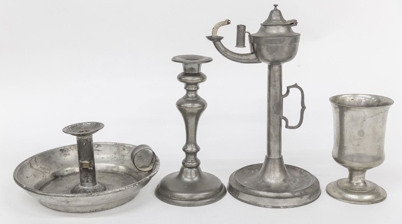 Pewter Lighting Plus: Lot of four including an American pewter candlestick 8" high; plus pewter whale oil lamp 5 1/2" diameter x 11" high; plus Sellew, Cincinnati pewter communion chalice, unmarked, 3 3/8" diameter x 5 3/4