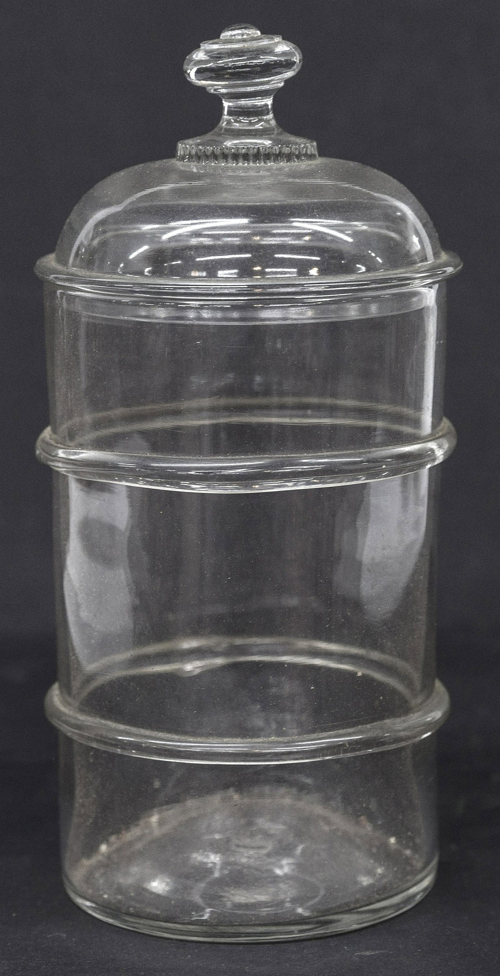 Blown Glass Store Jar: Clear with raised ribs, domed lid with knob finial, snap pontil on base, 5 1/4" diameter x 10 1/4" high. Condition Fine.