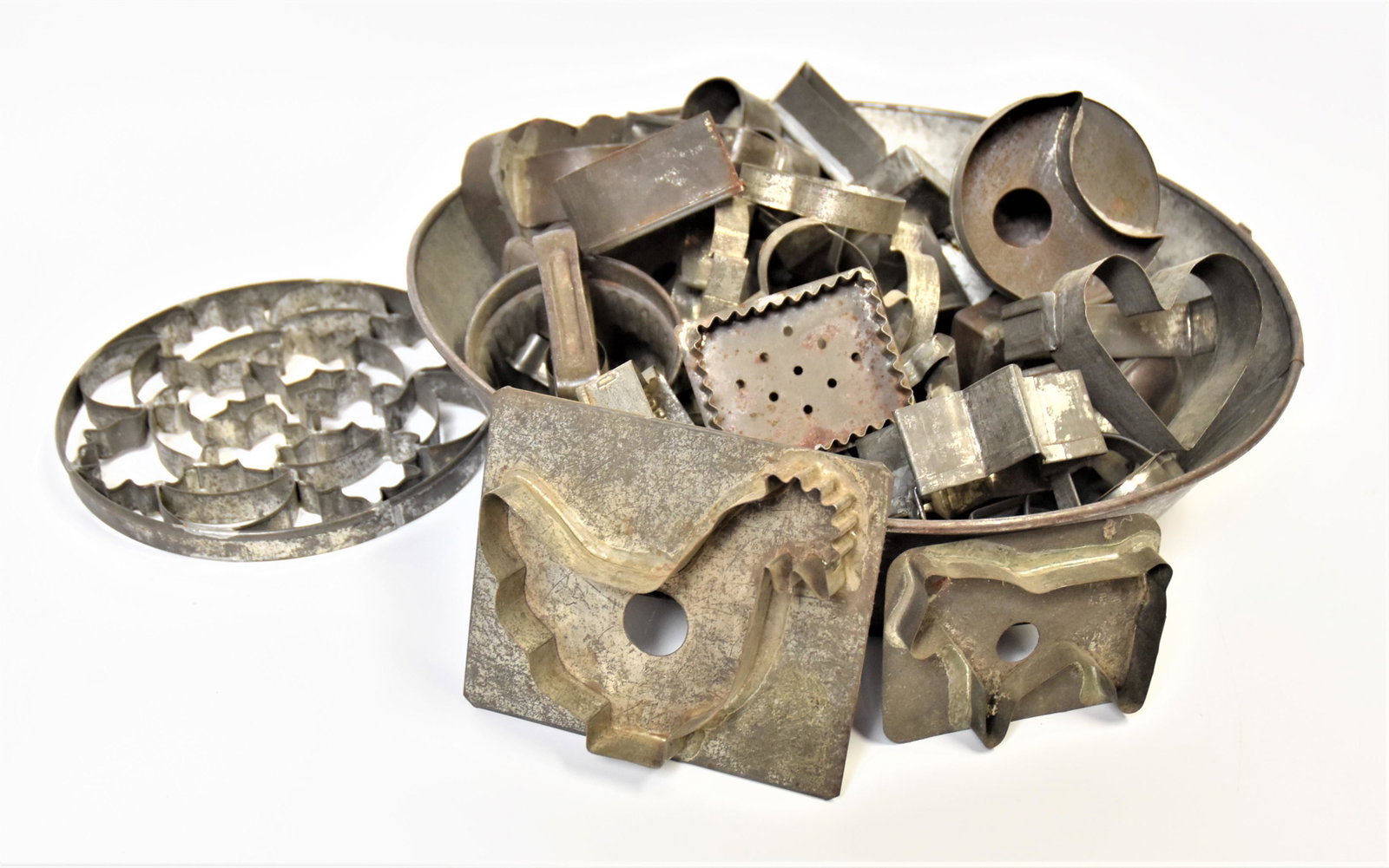 Early Tin Cookie Cutters Plus: Lot of 40, including many early animals, hearts moons, stars, geometric figures, biscuit cutters, brass pie crimper, brass picture rail hanger, two hat pins and larger tin pan, 15" diameter. Condition