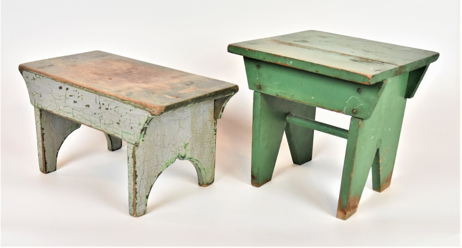 Two Early Painted Footstools: Both with cut-out ends and aprons, one 19th century in gray over green paint in white pine, 17" long x 9" wide & high, nice old patina; and early 20th century examle in original green paint, 12" squar