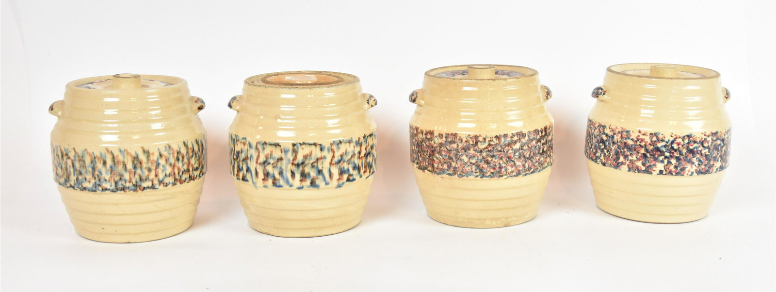 Four Spongeware Cookie Jars: Blue and red sponge band on yelloware bodies with handles and lids, 8" diameter x 8 1/2" high. Condition glued break on one lid, one lid only near match, line in another lid.