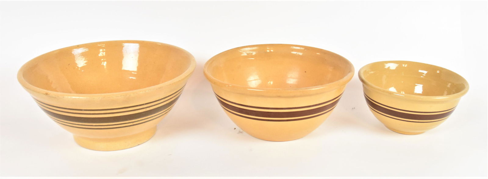 Three Yelloware Mixing Bowls: All 19th century with brown slip trailed banding, 12 3/8" diameter x 5 1/2" high; 10 1/2" diameter x 5" high & 8" diameter x 4 1/4" high. Condition all Fine.