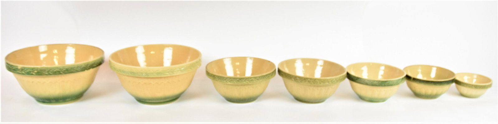Nested Yelloware Mixing Bowls: Lot of seven, matched set with relief floral and green highlights, largest is 12 1/4 x 6 1/4; smallest is 5 1/2" diameter x 2 3/4" high. Condition Very Good.