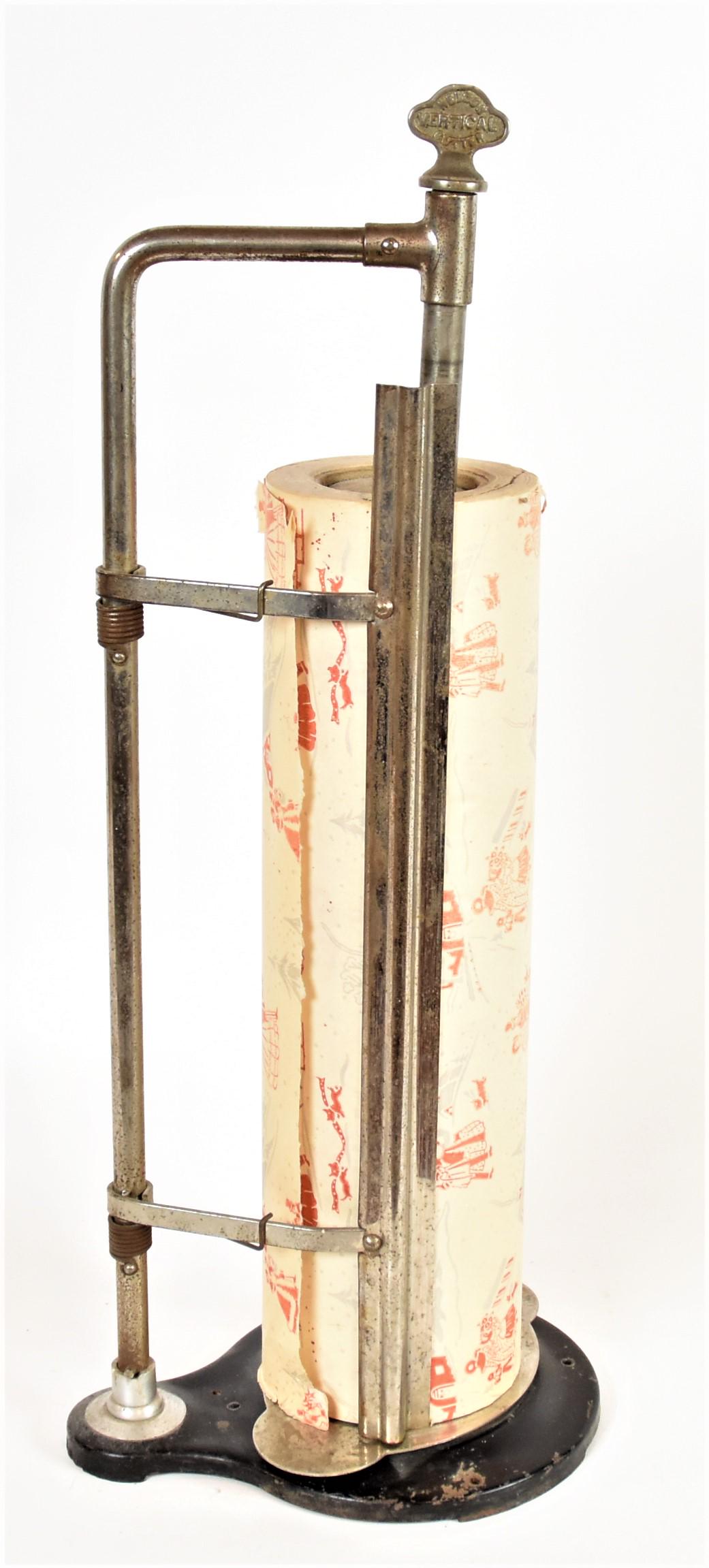 Nelson Country Store Wrapping Paper Cutter: Nickel plated steel with black painted base with top marked Nelson Vertical Cutter, 10 1/2 x 7 1/2 x 26" high, complete with a roll of Christmas wrapping paper on original wood roller mount, 18" wide.