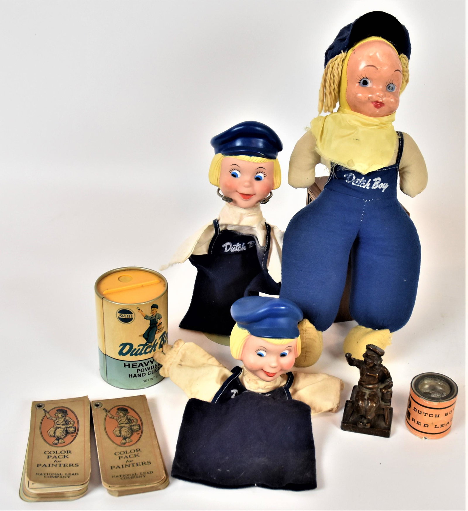 Dutch Boy Puppets Plus: Lot of eight including two rubber & cloth hand puppets, 11" high; plus cloth doll with cello face, 15" high; plus bronzed lead paper weight of seated figure with The Dutch Boy Painter along base, 4" h