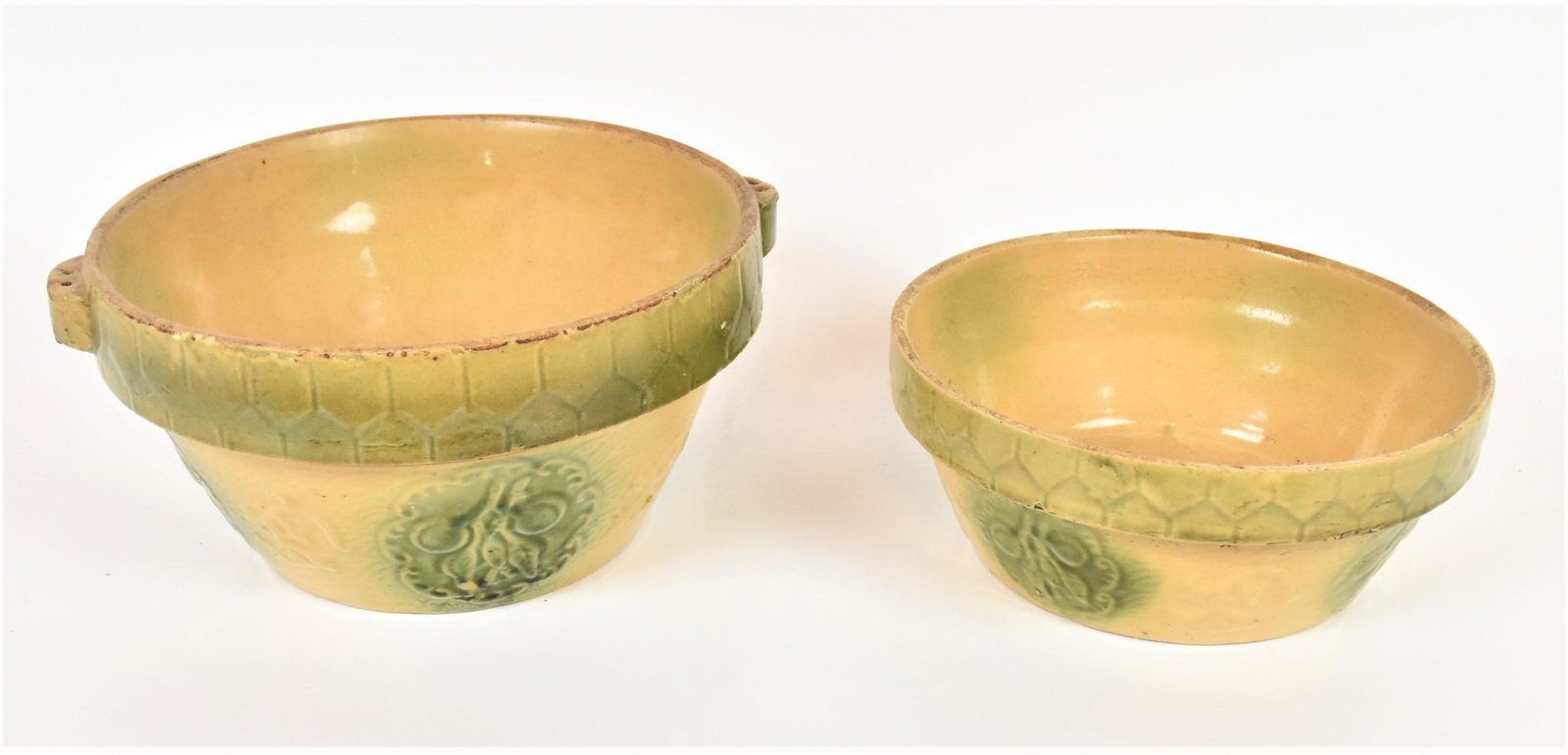 Two Cream & Green Mixing Bowls: Yelloware with relief molded floral decoration, largest is 11" diameter x 5 1/4" high; smallest is 9 1/2" diameter x 3 3/4" high. Condition Both Very Good.